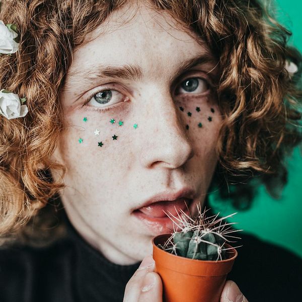 A person smiling gently while sitting at a desk with a plant, looking refreshed.